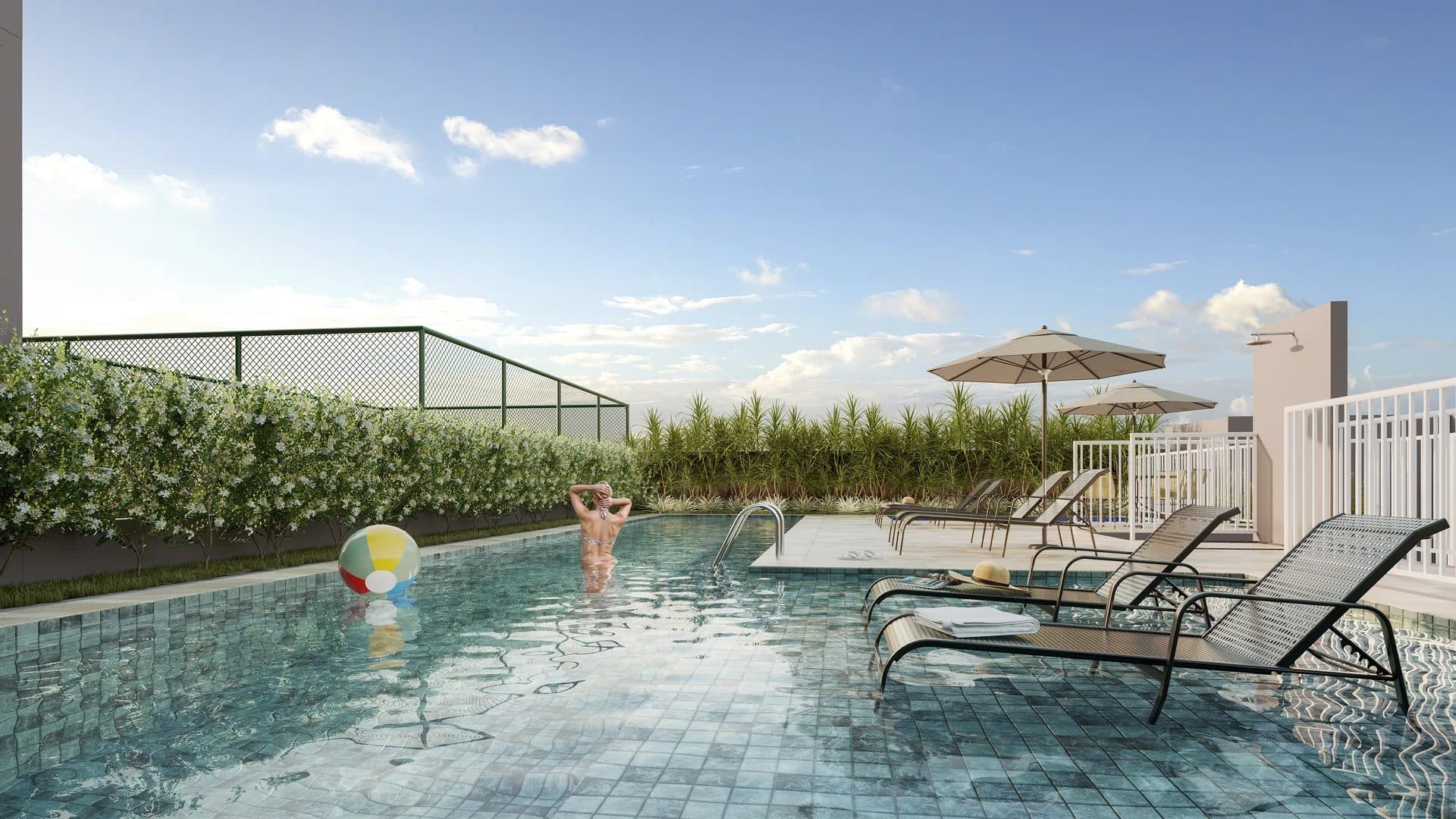 Piscina com espreguiçadeiras, guarda-sóis e área verde ao fundo.